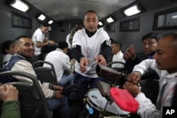 In this July 19, 2019 photo, inmate Martin Reano is passed an instrument inside an armored bus that will transport him and fellow inmates to the Peruvian capital for a classical music session at the national theater.