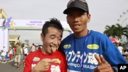 Japanese entertainer Neko Hiroshi, left, poses with Cambodian winner Em Buntin after a half marathon Saturday, June 18, 2011 in Phnom Penh, Cambodia. The Japanese finished second. More than 1,000 Cambodians and foreigners took part in the running, celebra
