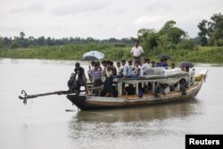 FILE - Rohingya Muslims travel on a boat along a river in Buthidaung township, Myanmar, on June 7, 2015.