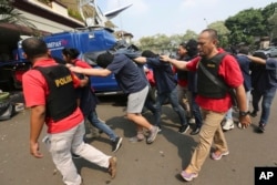 FILE - Police officers escort men arrested in a raid on a gay sauna at North Jakarta police headquarters in Jakarta, Indonesia, May 22, 2017. Indonesian police detained dozens of men in a weekend raid on a gay sauna in the capital.