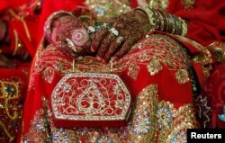 FILE - A bride holds her purse during a mass wedding ceremony in Karachi, Pakistan, May 9, 2016.