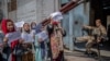 A Taliban fighter watches as Afghan women hold placards during a demonstration demanding better rights for women in front of the former Ministry of Women Affairs in Kabul on September 19, 2021.