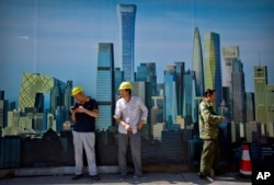 FILE - Workers smoke outside of a construction site in the central business district in Beijing, Sept. 22, 2017.