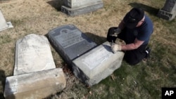A Trump supporter named Bob, who declined to give his last name, volunteers his time and prepares the base of a damaged headstone, Feb. 28, 2017, in Philadelphia. Scores of volunteers are expected to help in an organized effort to clean up and restore the Jewish cemetery where vandals damaged hundreds of headstones.