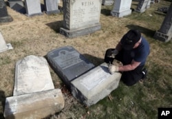 Trump supporter Bob, who declined to give his last name, volunteers his time and prepares the base of a damaged headstone, Feb. 28, 2017, in Philadelphia. Scores of volunteers are expected to help in an organized effort to clean up and restore the Jewish cemetery where vandals damaged hundreds of headstones.