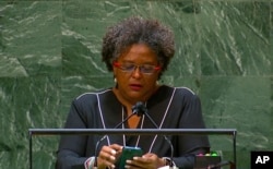 FILE - Mia Amor Mottley, prime minister of Barbados, reads from a phone as she addresses the 76th Session of the U.N. General Assembly at U.N. headquarters, Sept. 24, 2021.