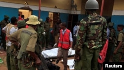 Police officers stand by dead bodies after an attack by Islamist militants from the Somali group al-Shabab in Mandera, Kenya, Oct. 6, 2016.