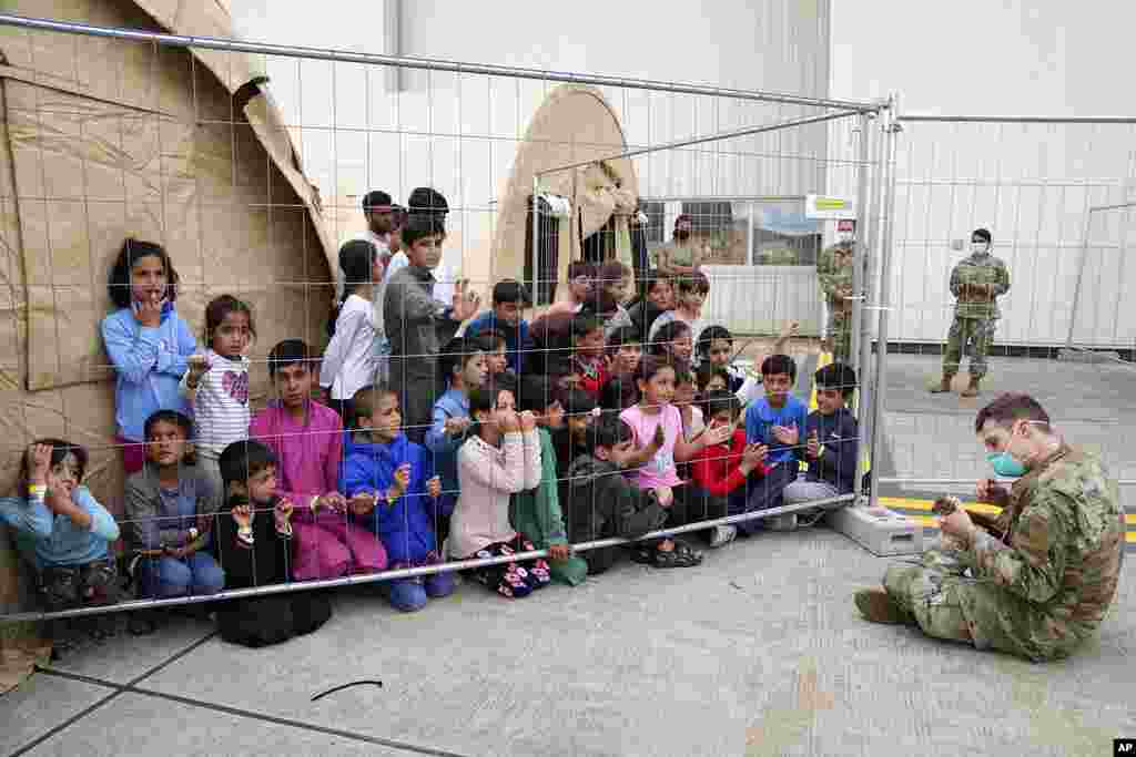 A U.S. soldier plays guitar for recently evacuated Afghan children at the Ramstein U.S. Air Base, Germany.