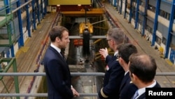 French President Emmanuel Macron (L) listens to explanations in front of a nuclear submarine as part of his visit to the Ile Longue Defence unit, submarine navy base, in Crozon, near Brest, western France, July 4, 2017. 