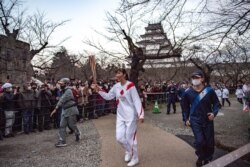 Motoko Obayashi (tengah), mantan pemain bola voli Olimpiade Jepang, berlari dengan membawa obor pada hari kedua estafet obor Olimpiade Tokyo 2020, 26 Maret 2021.