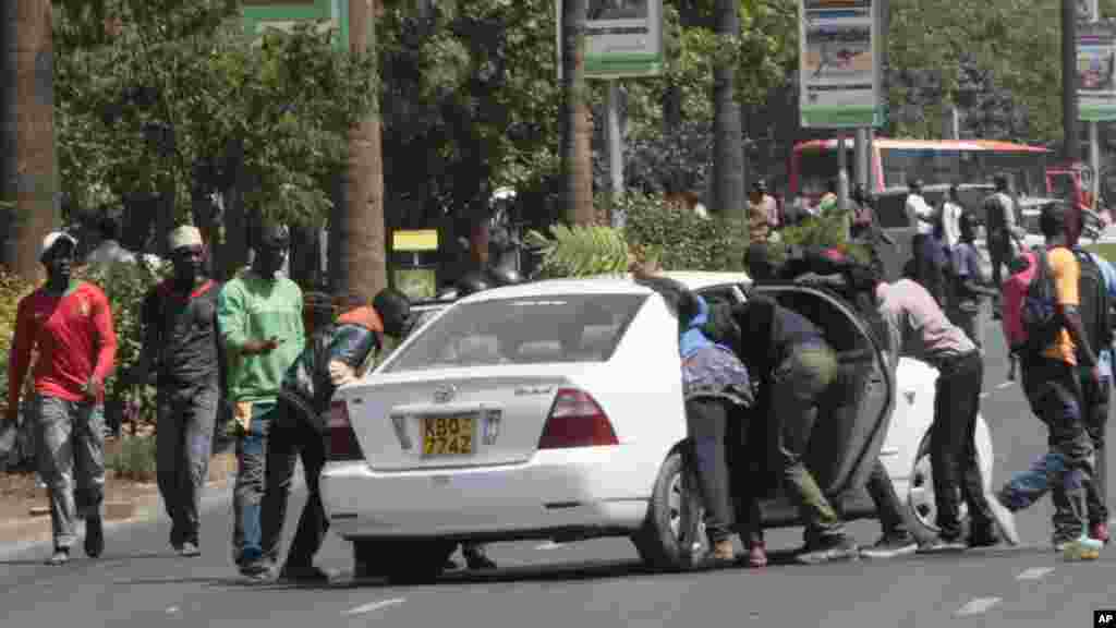 University students harass a motorist during a demonstration in Nairobi,, Kenya, Tuesday, Sept, 22, 2015.