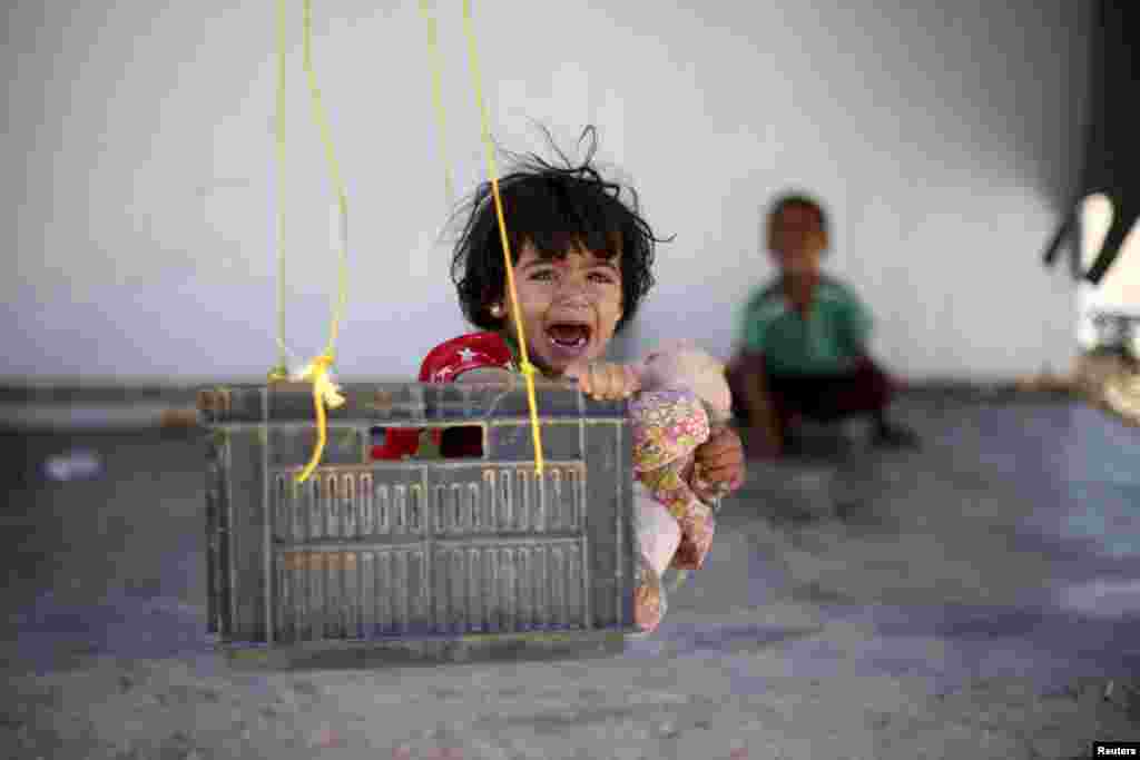 A Syrian refugee child reacts while sitting in a swing in Al Zaatari refugee camp, in the Jordanian city of Mafraq, near the border with Syria, Sept. 19, 2015.