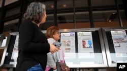FILE - Newseum visitors browse newspaper front pages displayed outside the museum in Washington, June 11, 2018. 
