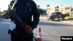 A security officer stands with his weapon on a road leading to a police station in Benghazi, Dec. 4, 2014. 
