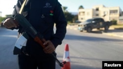 A security officer stands with his weapon on a road leading to a police station in Benghazi, Dec. 4, 2014. 