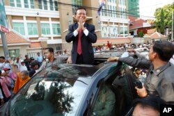 FILE - Cambodia's main opposition Cambodia National Rescue Party Deputy President and National Assembly Deputy President Kem Sokha greets to his supporters outside the Phnom Penh Municipality Court in Phnom Penh, Wednesday, April 8, 2015.