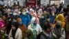 Para penumpang kereta api mengenakan masker sebagai pencegahan virus corona, di stasiun di Surabaya, 15 Maret 2020. (Foto: AFP)