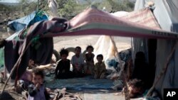 FILE - Displaced children pose for a photo as they sit in their family's tent at a camp for internally displaced people in the outskirts of Sana'a, Yemen, June 8, 2016.