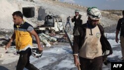 Syrian civil defense members search near a burned vehicle and personal belongings at a site in Hass town after an airstrike in the southern part of Syria's Idlib province, Sept. 8, 2018.