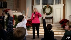 Democratic presidential candidate Hillary Clinton, center, takes questions as children raise their hands during a town hall style campaign event Tuesday, Dec. 29, 2015, at South Church, in Portsmouth, N.H. (AP Photo/Steven Senne)