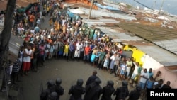 Pasukan keamanan Liberia berdiri di depan para demonstran menyusul bentrokan di daerah West Point di Monrovia (20/8). 