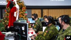 In this photo provided by the North American Aerospace Defense Command, 22 Wing members are seen showing how they track Santa on his sleigh on Christmas Eve during a media preview at the Canadian Forces Base in North Bay on Dec. 9, 2021.