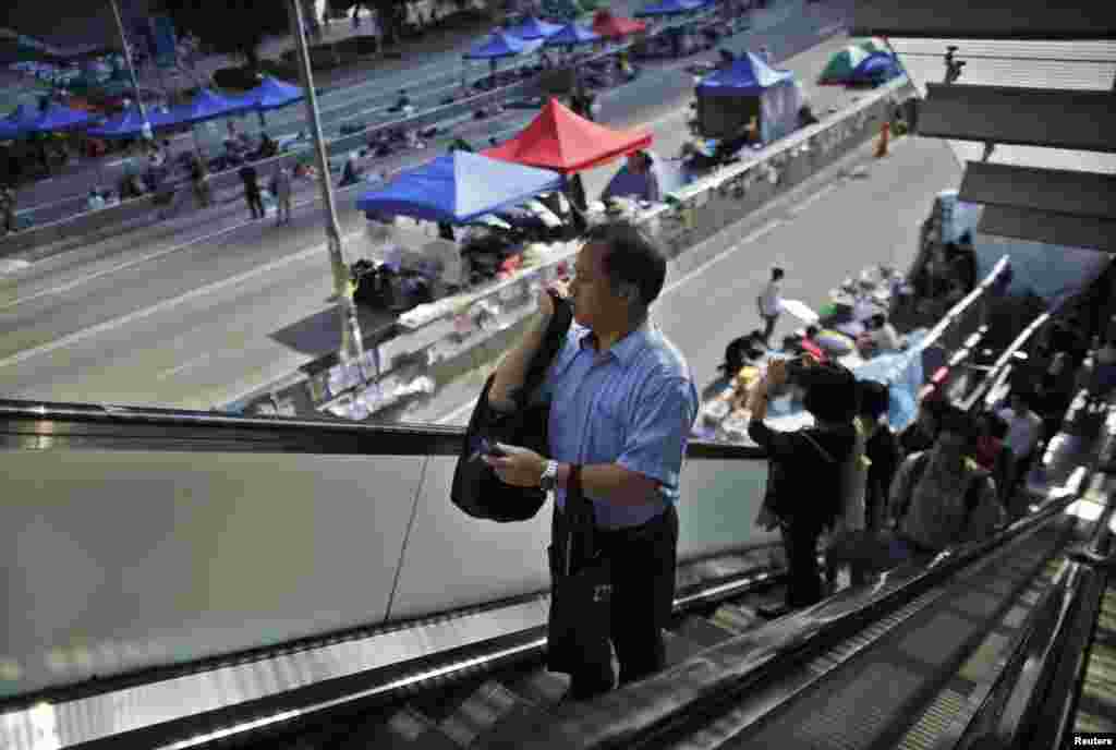 Government employees arrive to work as they walk along an area occupied by protesters outside of the government headquarters building in Hong Kong, Oct. 6, 2014.