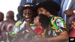 Zimbabwean President Robert Mugabe and his wife Grace, right, share a light moment with their grandson during his 93rd Birthday celebrations in Matopos on the outskirts of Bulawayo, Saturday, Feb. 25, 2017. Mugabe is celebrating his 93rd birthday amid granite hills were spirits are said to dwell, defying calls to resign after nearly four decades in power with a celebration in in a region for opposing a leader who says he will run again in 2018 elections(AP Photo/Tsvangirayi Mukwazhi)