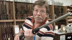 John Kinkade sostiene un rifle en la tienda de armas que administra en Iowa.