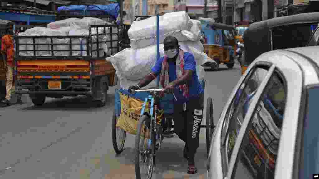 အိန္ဒိယနိုင်ငံ Hyderabad မြို့မှာ&nbsp;တွေ့ရတဲ့ ကုန်တွေတင်ထားတဲ့ ဆိုက်ကားတစီးနဲ့&nbsp;နှာခေါင်းစည်း တပ်ထားတဲ့ အမျိုးသားတဦး။ (ဇွန် ၂၅၊ ၂၀၂၀)