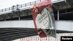 FILE - A huge banner depicting U.S. President Barack Obama wearing a T-shirt wishing Russia's President Vladimir Putin a happy birthday, hangs on a bridge in Moscow, Oct. 7, 2014.