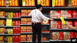 An employee stands on a stepladder as she stocks boxes of mooncakes at a supermarket in Beijing, Wednesday, Sept. 14, 2016. 