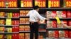 An employee stands on a stepladder as she stocks boxes of mooncakes at a supermarket in Beijing, Wednesday, Sept. 14, 2016. 