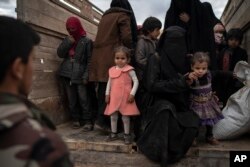 Women and children exit the back of a truck to be screened by U.S.-backed Syrian Democratic Forces after being evacuated out of the last territory held by Islamic State militants, in the desert outside Baghuz, Syria, Feb. 27, 2019.