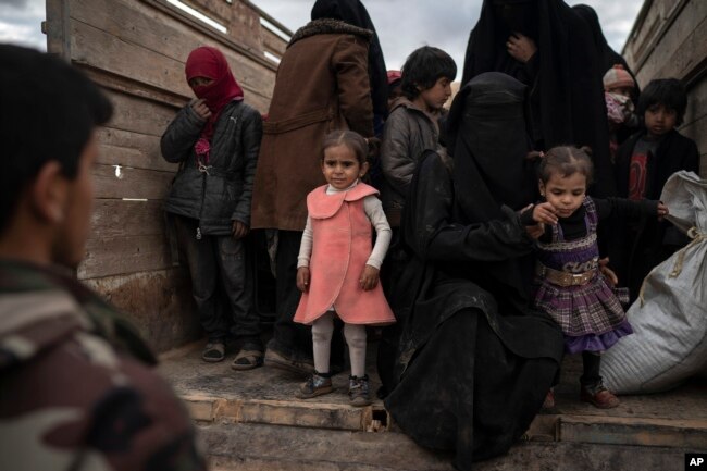 Women and children exit the back of a truck to be screened by U.S.-backed Syrian Democratic Forces after being evacuated out of the last territory held by Islamic State militants, in the desert outside Baghuz, Syria, Feb. 27, 2019.