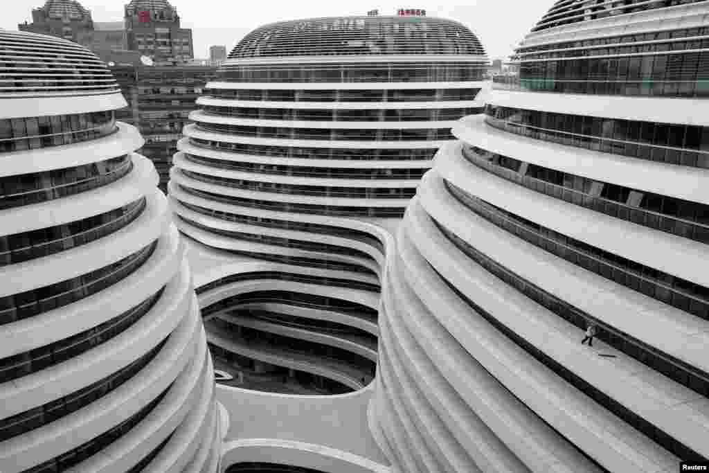 A worker cleans the exterior of a newly built urban complex building accommodating offices and retail shops in Beijing, China, Oct. 14, 2013. 