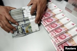 중국 산시성 타이위안의 한 은행에서 직원이 위안화와 달러화를 세고 있다.