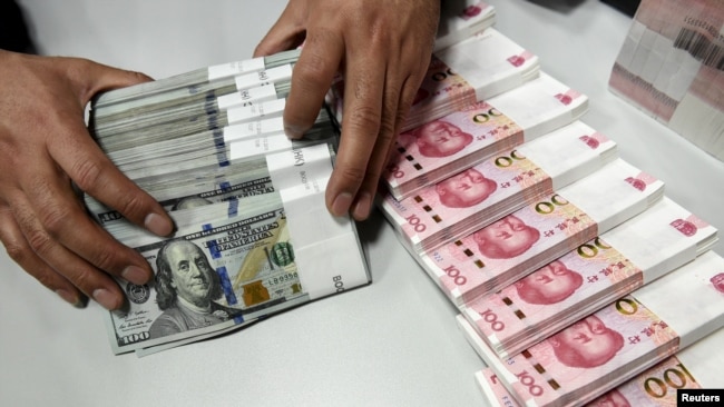 一名中国的银行职员在点数美元和人民币。(资料照片)