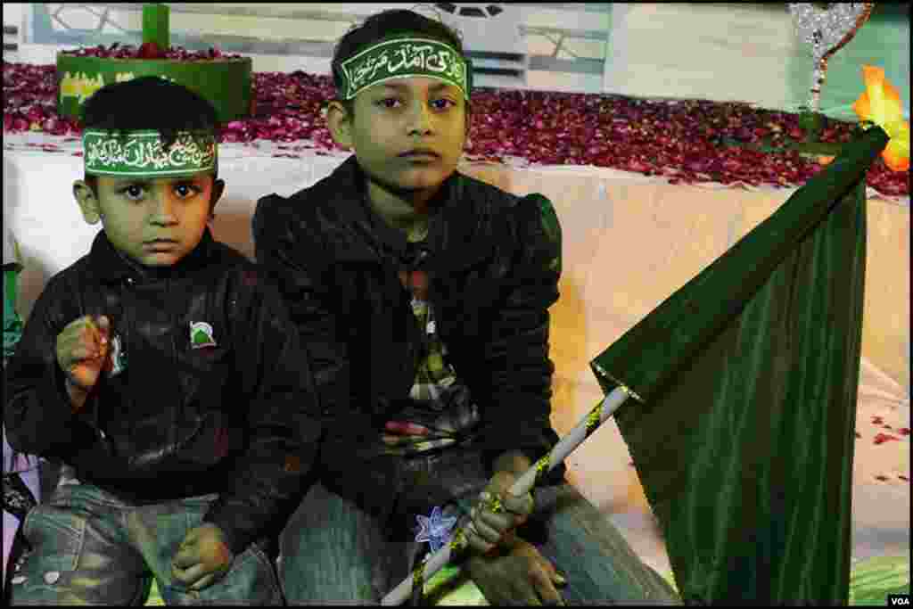 دو بچے سبز پرچم لئے ماتھے پر عقیدت کے طور پر سبز پٹیاں باندھے ہوئے