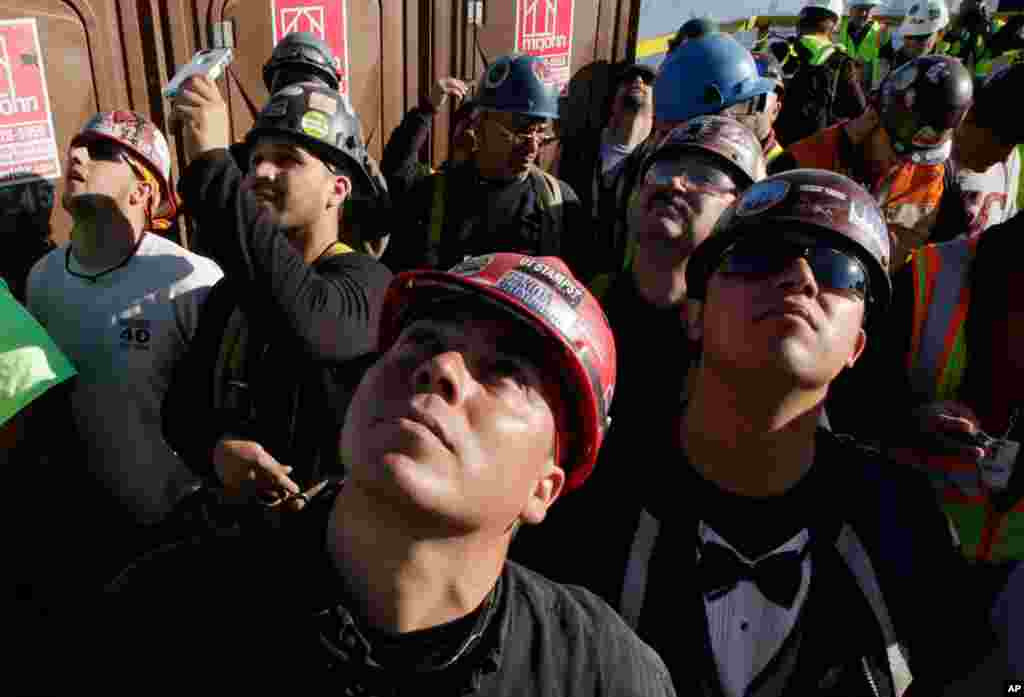 Iron workers gather on the roof of One World Trade Center to watch as the final piece of spire is hoisted in place.