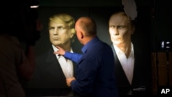 A journalist points at a portrait of U.S. President-elect Donald Trump, with a portrait of Russian President Vladimir Putin at right, at the Union Jack pub in Moscow, Russia, Nov. 9, 2016. The Trump campaign is denying it had contacts with Russian officials.