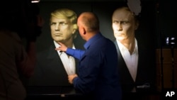 2016年11月9日，一名俄罗斯记者用手指指着川普的画像。右边是普京总统的画像。