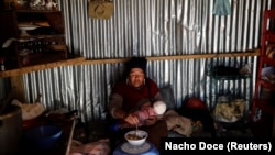 Eva Chura, 42, a 'pallaquera' known as a gold picker, breastfeeds her three-month-old son Alizon, as she eats inside their room in La Rinconada, the Andes, Peru, October 11, 2019. (REUTERS/Nacho Doce )