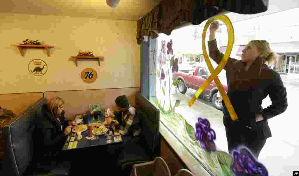 Jammi Parris, a waitress at the Blue Bird Cafe, paints a yellow ribbon on a window in downtown Arlington, Washington, March 25, 2014.