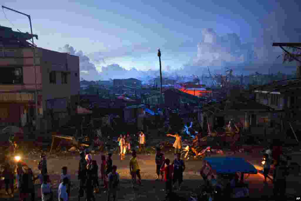 Para penyintas Topan Haiyan menunggu di pinggir jalan di sebuah kota yang hancur di Guiuan, Filipina (14/11). (AP/David Guttenfelder)