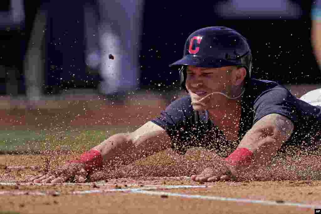 Cleveland Indians Jake Bauers slides home to score on a hit by Josh Naylor during the first inning of a spring training baseball game against the Seattle Mariners, March 2, 2021, in Peoria, Arizona.