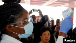 Un agent de la santé prélève la température des arrivants à l'aéroport dans le cadre de la prévention contre Ebola, à Monrovia, Liberia.
