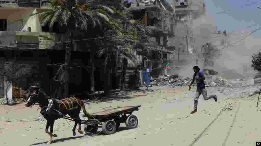 A Palestinian flees after an Israeli strike hits a three-story building belonging to the Abdul Hadi family in Gaza City in the northern Gaza Strip, Aug. 24, 2014. 