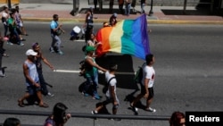 Revellers hold a rainbow flag as they take part in the gay pride parade in Caracas, Venezuela, July 3, 2016. 
