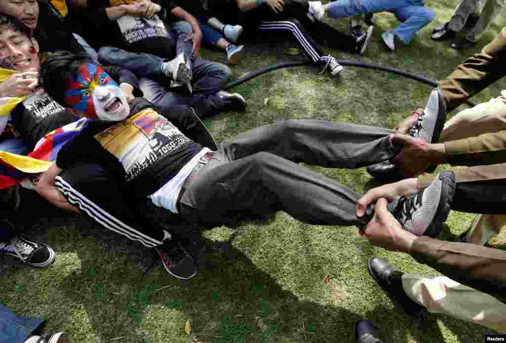 Police officers detain a Tibetan during a protest held to mark the 60th anniversary of the Tibetan uprising against Chinese rule, outside the Chinese embassy in New Delhi, India.